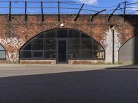 an old brick building with graffiti on the outside and some windows in the back ground