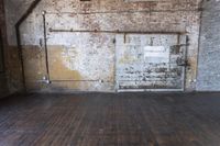 an old warehouse has a wooden floor and door in it, next to a brick wall and stairs
