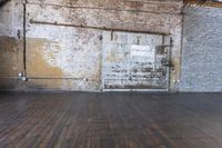 an old warehouse has a wooden floor and door in it, next to a brick wall and stairs