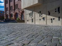 cobblestone driveway surrounded by modern buildings on sunny day with sun reflecting onto the windows