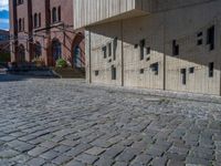 cobblestone driveway surrounded by modern buildings on sunny day with sun reflecting onto the windows