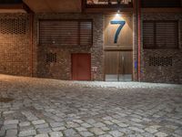 a brick building with a door in the middle of it at night with a fire hydrant outside