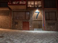 a brick building with a door in the middle of it at night with a fire hydrant outside