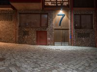 a brick building with a door in the middle of it at night with a fire hydrant outside