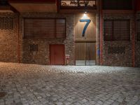 a brick building with a door in the middle of it at night with a fire hydrant outside