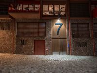 a brick building with a door in the middle of it at night with a fire hydrant outside