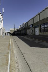 this is a very empty street at the curbside of a factory building with one side in motion