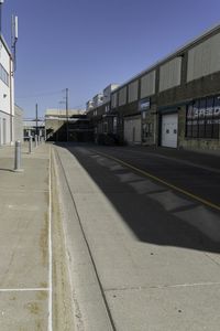 this is a very empty street at the curbside of a factory building with one side in motion