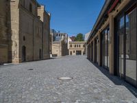 the sidewalk is paved with stones and has a bench in front of it, with no people inside