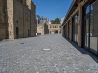 the sidewalk is paved with stones and has a bench in front of it, with no people inside