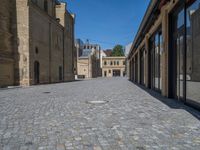 the sidewalk is paved with stones and has a bench in front of it, with no people inside