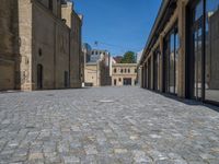 the sidewalk is paved with stones and has a bench in front of it, with no people inside