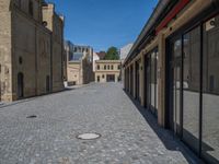 the sidewalk is paved with stones and has a bench in front of it, with no people inside