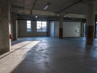 a empty warehouse room with windows and concrete walls, in the afternoon sun light coming through