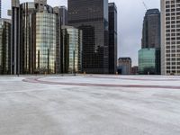 a paved square in front of many tall skyscrapers is pictured in this image with one fire hydrant at the center