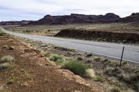 the view looking down the road from a hill at an arid area with grass, rocks and mountains