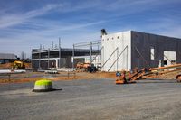 workers with equipment working at a construction site under blue skies and clouds in the background