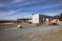 workers with equipment working at a construction site under blue skies and clouds in the background