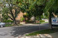 a moving truck on the street near a house and palm trees that are growing by the sidewalk