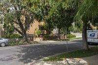 a moving truck on the street near a house and palm trees that are growing by the sidewalk