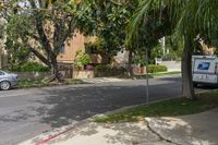 a moving truck on the street near a house and palm trees that are growing by the sidewalk