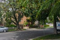 a moving truck on the street near a house and palm trees that are growing by the sidewalk