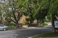 a moving truck on the street near a house and palm trees that are growing by the sidewalk