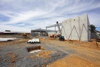 a construction site being built with large concrete walls and beams under a partly cloudy sky