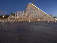 a large wooden roller coaster and some building equipment and lights at night time or at work