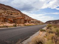 the road in the middle of a desert area that is winding through the mountain landscape