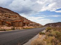 the road in the middle of a desert area that is winding through the mountain landscape