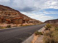 the road in the middle of a desert area that is winding through the mountain landscape