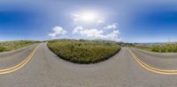 a curved road going down the mountain, with a sun in the middle of the view