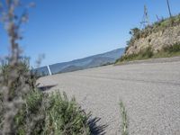 the street is paved and empty of people and motorcycles parked near a mountain area and trees