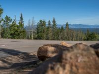 the mountains are visible in the distance from this wide, empty road, overlooking a wide landscape and forest