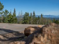 the mountains are visible in the distance from this wide, empty road, overlooking a wide landscape and forest