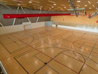 an indoor gym with basketball hoops and multiple lanes in the floor, with lights on all sides