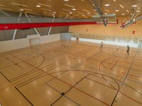 an indoor gym with basketball hoops and multiple lanes in the floor, with lights on all sides