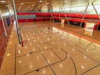 an empty gymnasium with hardwood floors, painted red and light orange and glass flooring