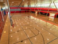 an empty gymnasium with hardwood floors, painted red and light orange and glass flooring