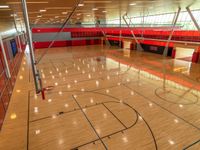 an empty gymnasium with hardwood floors, painted red and light orange and glass flooring