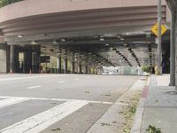 a yellow bicycle sits parked under a bridge in an empty city space for pedestrians and pedestrians