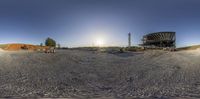 some sand in front of the sun, and a few other people on some dirt