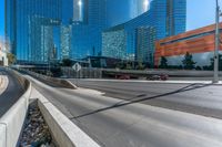 tall glass towers are rising into the sky near a freeway and sidewalk with a bicycle