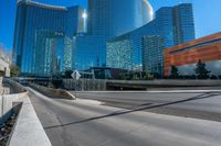 tall glass towers are rising into the sky near a freeway and sidewalk with a bicycle