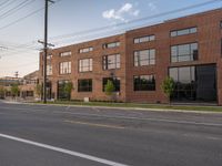 an empty street in front of a large red brick building on the other side of the road is a street light that has a line for motorists