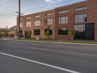 an empty street in front of a large red brick building on the other side of the road is a street light that has a line for motorists