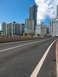 a very wide road next to a very tall building near the water with people walking on it