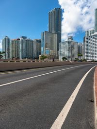 a very wide road next to a very tall building near the water with people walking on it