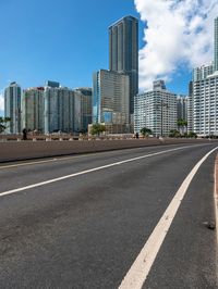 a very wide road next to a very tall building near the water with people walking on it